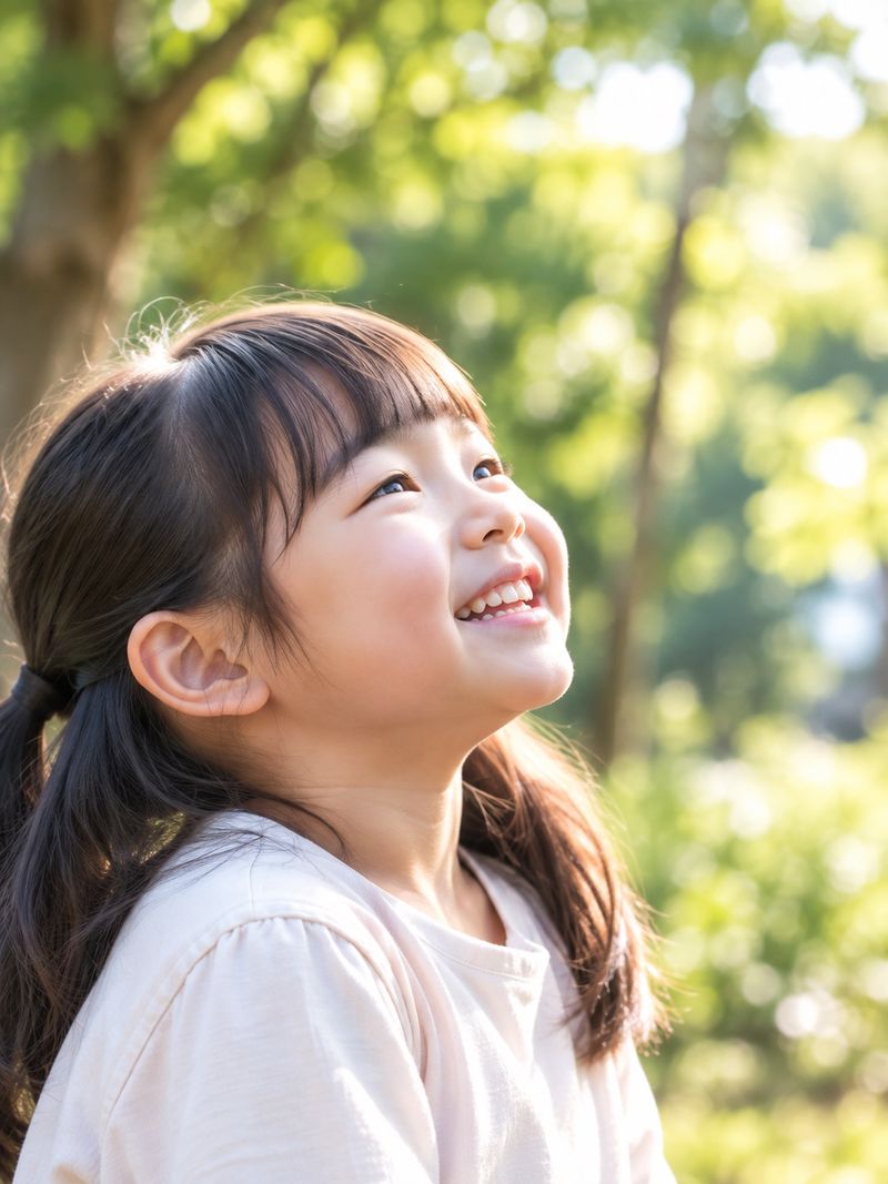 木もれ日の中で空を見上げて笑う女の子